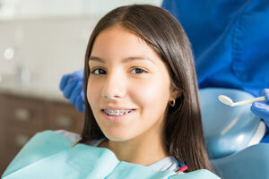 a girl smiles during a visit to her adolescent orthodontist