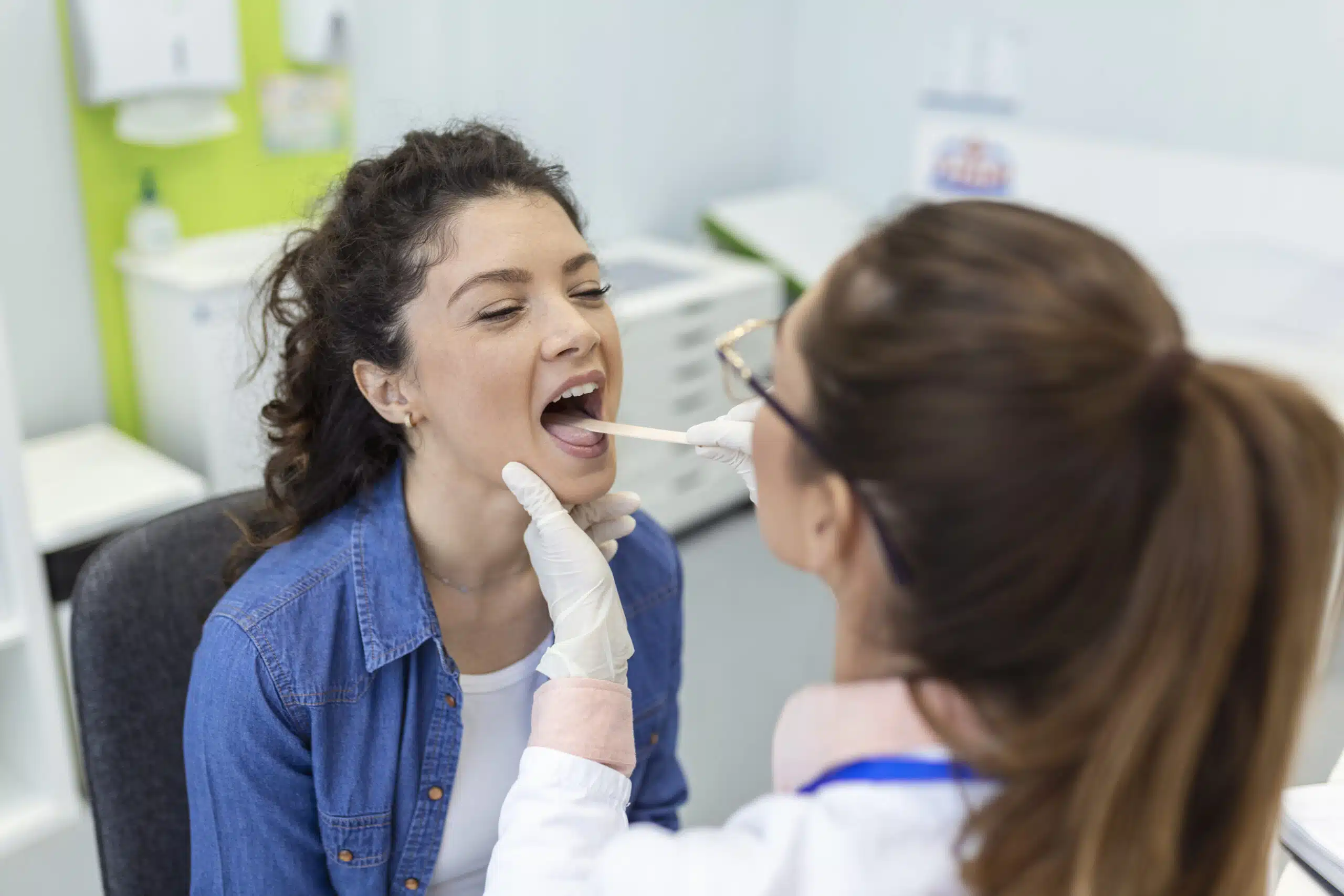 Female patient opening her mouth for the doctor to look in her throat. Otolaryngologist examines sore throat of patient. Orthodontic Care in Houston for All Ages