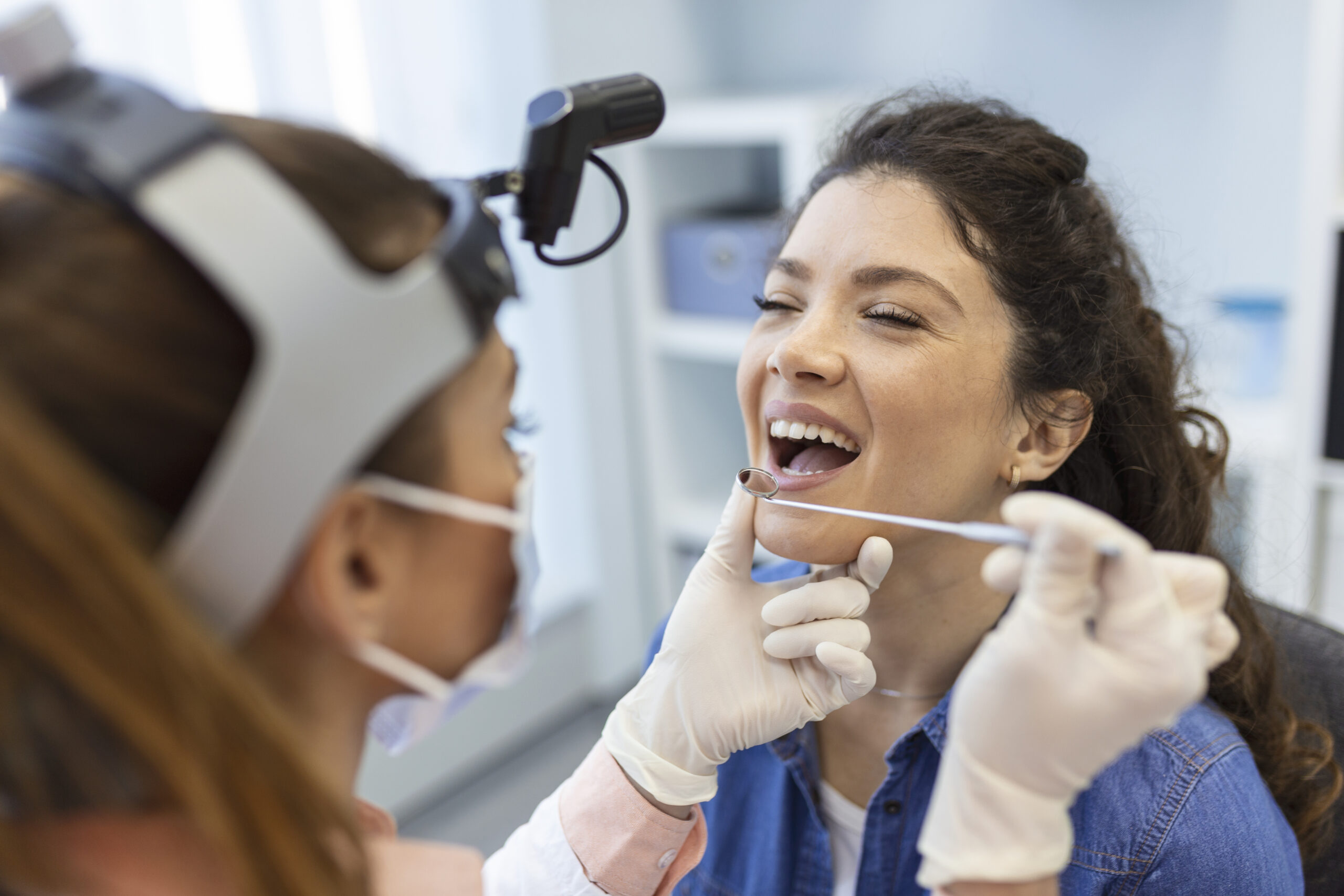 Female patient opening her mouth for the doctor to look in her throat. Otolaryngologist examines sore throat of patient.