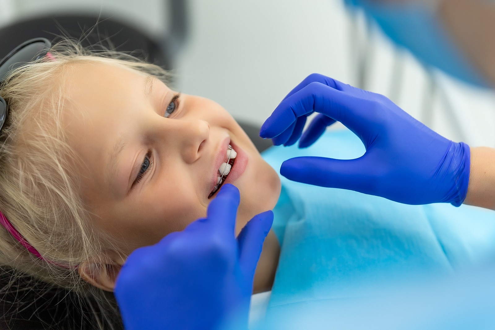 Young child wearing kids braces while an orthodontic professional checks alignment