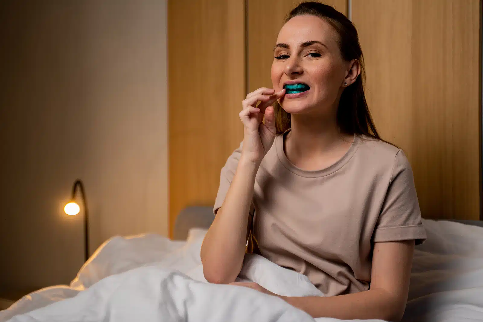 Woman inserting a custom oral sleep device as part of snoring treatment