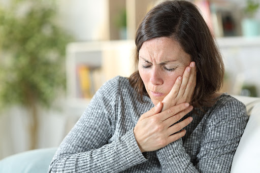 Woman holding her jaw in pain illustrating TMJ treatment options and jaw discomfort symptoms