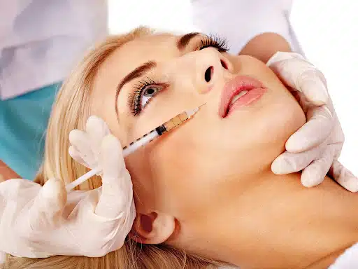Cosmetic specialist performing dermal filler procedure for facial contouring on a woman’s cheek area